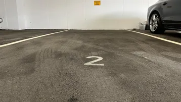 Tiefgaragenstellplatz Nummer 2 mit asphaltiertem Boden und weiß gestrichenen Wänden.