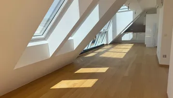 Helles Dachgeschosszimmer mit Holzboden, großen Dachfenstern und viel natürlichem Licht.