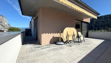 Geräumige Terrasse mit Fliesenboden, Markise und weitem Blick auf die umliegende Landschaft.