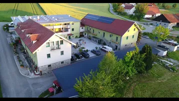 Luftaufnahme eines ländlichen Anwesens mit mehreren Gebäuden, Innenhof und angrenzenden Feldern bei Sonnenuntergang.