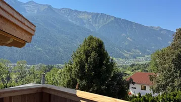 Neuer Holzbalkon mit atemberaubendem Blick auf die majestätische Berglandschaft und das grüne Tal.