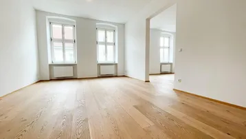 Helles, leeres Zimmer mit neuem Parkettboden und zwei Fenstern, bereit zur individuellen Gestaltung.