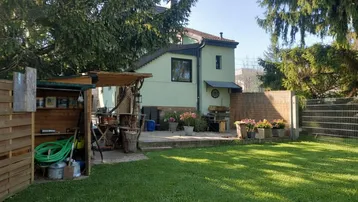 Gepflegter Garten mit Rasenfläche, Terrasse und Gartenhaus hinter dem Wohngebäude.