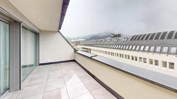 Geräumige Dachterrasse mit Fliesenboden und weitem Blick auf die umliegende Stadt und Berge.
