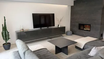 Helles Wohnzimmer mit modernem Kamin, großem Fernseher und bequemer Sitzecke.