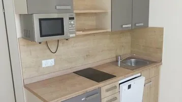 Kleine, moderne Küchenzeile mit integrierten Geräten und Holzoptik-Arbeitsplatte.
