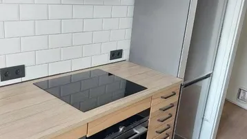 Moderne Küche mit Induktionskochfeld, Backofen, Geschirrspüler und Kühlschrank.