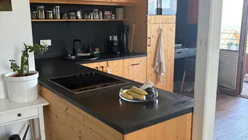 Moderne Holzküche mit schwarzen Arbeitsplatten, integriertem Backofen und Kücheninsel.