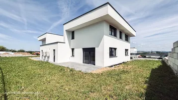 Neubau-Einfamilienhaus mit moderner Architektur und ungestaltetem Gartenbereich.