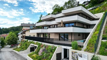 Modernes Mehrfamilienhaus in Hanglage mit Terrassen, Balkonen und integrierter Tiefgarage.