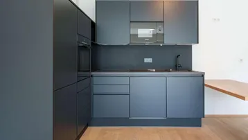 Moderne Einbauküche in Anthrazit mit integrierten Geräten und Holztheke.
