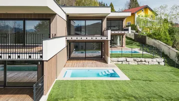 Moderne Architektur mit mehreren Wohneinheiten, privaten Pools und gepflegten Rasenflächen in Hanglage.