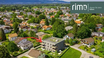 Luftaufnahme eines modernen Wohngebäudes in einer grünen Wohngegend mit Bergblick.