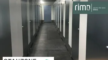 Langer, gut beleuchteter Flur in einer modernen Lagerhalle mit vielen individuellen Lagereinheiten und Betonboden.