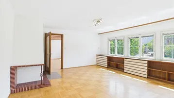 Geräumiges Wohnzimmer mit Parkettboden und einem dekorativen Kaminbereich.