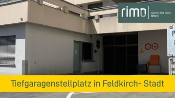 Eingangsbereich einer Tiefgarage mit Hinweisschildern und Gebäudefassade im Hintergrund.