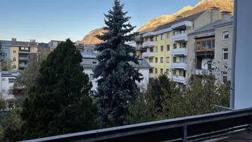 Balkon mit Blick auf die umliegenden Gebäude und die majestätischen Berge im Hintergrund.