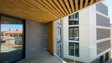 Moderner Balkon mit Holzelementen an der Decke und Glasgeländer, bietet einen Blick auf die Umgebung.