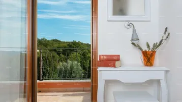 Zugang zu einem Balkon mit weitem Blick ins Grüne, ergänzt durch eine kleine Konsole im Innenbereich.