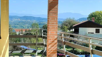 Geräumiger Balkon mit Fliesenboden, Ziegelpfeiler und weitem Blick auf die umliegende Berglandschaft.