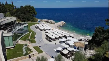 Panoramablick auf ein modernes Resort mit Strand, Meer und zahlreichen Sonnenschirmen.