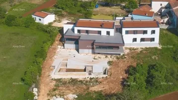 Luftaufnahme eines modernen Hauses im Bau mit Rohbau des Pools und umliegender Landschaft.