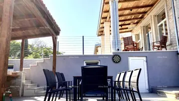 Geräumige Terrasse mit Esstisch und Stühlen, ideal für Mahlzeiten im Freien unter einer Holzpergola.