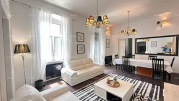 Helles Wohn- und Esszimmer mit weißen Sofas, dunklem Holzboden und einem großen Esstisch.