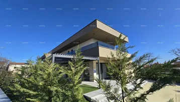 Moderne Villa mit gepflegtem Vorgarten und zeitgenössischer Architektur unter blauem Himmel.