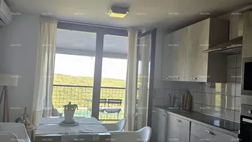 Offener Wohnbereich mit Essplatz, Zugang zum Balkon und moderner Küche im Hintergrund.