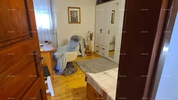 Helles Schlafzimmer mit Holzboden, weißem Kleiderschrank und einem Arbeitsbereich am Fenster.