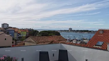 Geräumige Dachterrasse mit Liegestühlen und weitem Blick über die Stadt und das Meer.