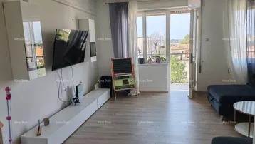 Helles Wohnzimmer mit modernem Entertainment-Bereich, Laminatboden und Zugang zum Balkon.