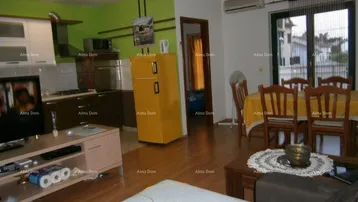 Offener Wohn-Essbereich mit integrierter Küche, Holzboden und Zugang zum Balkon.
