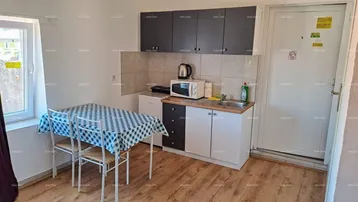 Kleine Küchenzeile mit Esstisch, Mikrowelle und Kühlschrank, ideal für einfache Mahlzeiten.