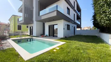 Moderne Wohnanlage mit privatem Pool und gepflegtem Rasenbereich unter strahlend blauem Himmel.