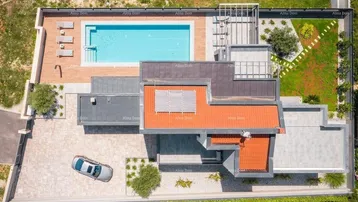 Luftaufnahme der modernen Villa mit Pool, Gartenanlage und Zufahrt.