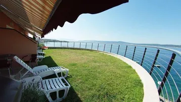 Große Rasenfläche mit Liegestühlen und Markise, direkt am Meer gelegen mit weitem Meerblick.