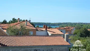 Panoramablick über die Dächer der Stadt mit dem Meer und grünen Hügeln in der Ferne.