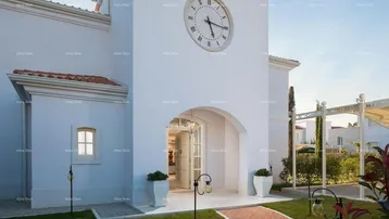 Elegante weiße Fassade eines Gebäudes mit einem großen Uhrturm und gepflegtem Vorgarten.