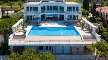 Luxuriöse Villa mit großem Poolbereich und Meerblick, umgeben von gepflegten Gärten.