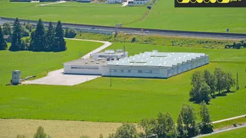 Luftaufnahme eines modernen Innovationszentrums mit weitläufigen Grünflächen, Autobahnanbindung und ländlicher Umgebung.
