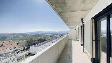 Langer Balkon mit Fliesenboden und weitem Blick über die Landschaft und Stadt.