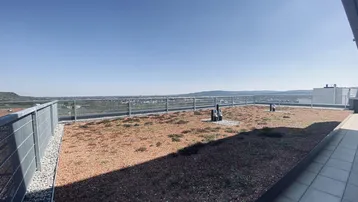 Dachterrasse mit weitem Blick über die Landschaft und teilweise begrünter Fläche.