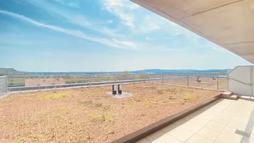 Große Dachterrasse mit Grünfläche und weitem Blick über die Landschaft und die Stadt.