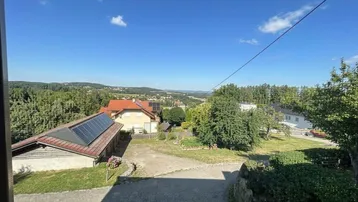 Weitläufiger Blick über die ländliche Umgebung mit Häusern, Bäumen und einem Solardach.