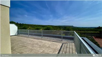 Große Dachterrasse mit Fliesenboden, Metallgeländer und weitem Blick über die grüne Landschaft und Weinberge.