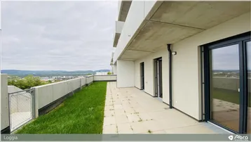 Geräumige Loggia mit Fliesenboden und Grünfläche, bietet einen weiten Ausblick über die Landschaft.