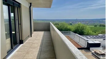 Geräumiger Balkon mit Fliesenboden und weitem Blick über die Landschaft unter blauem Himmel.
