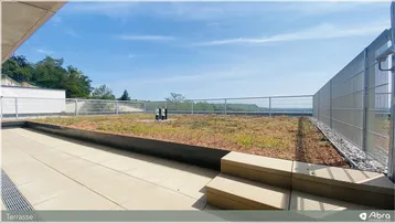 Große Dachterrasse mit Fliesenboden, Gründach und weitem Ausblick in die Landschaft.